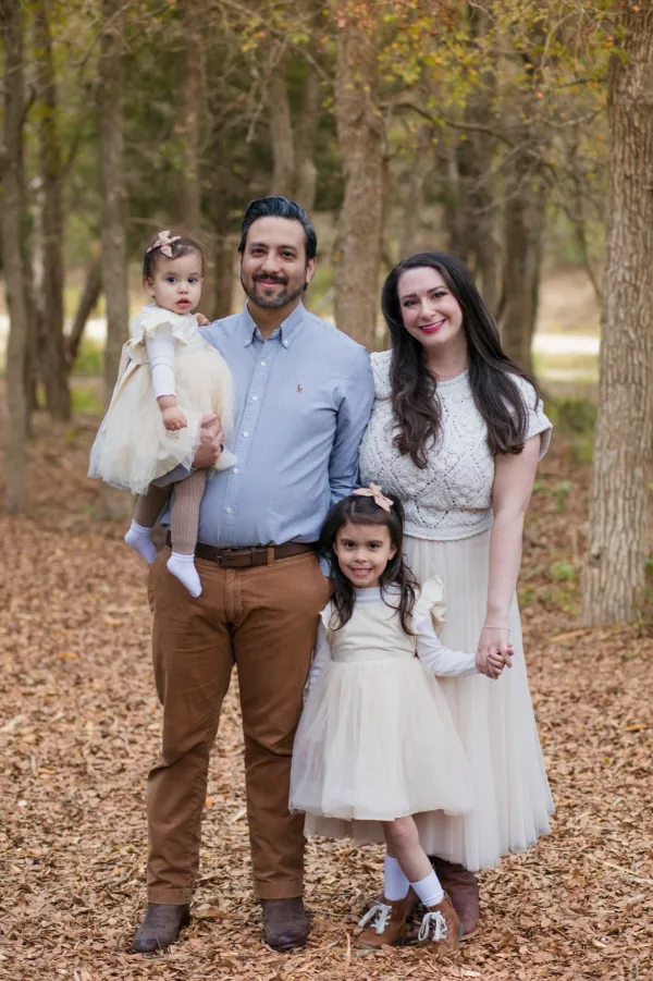 A family of four among fall leaves at golden hour